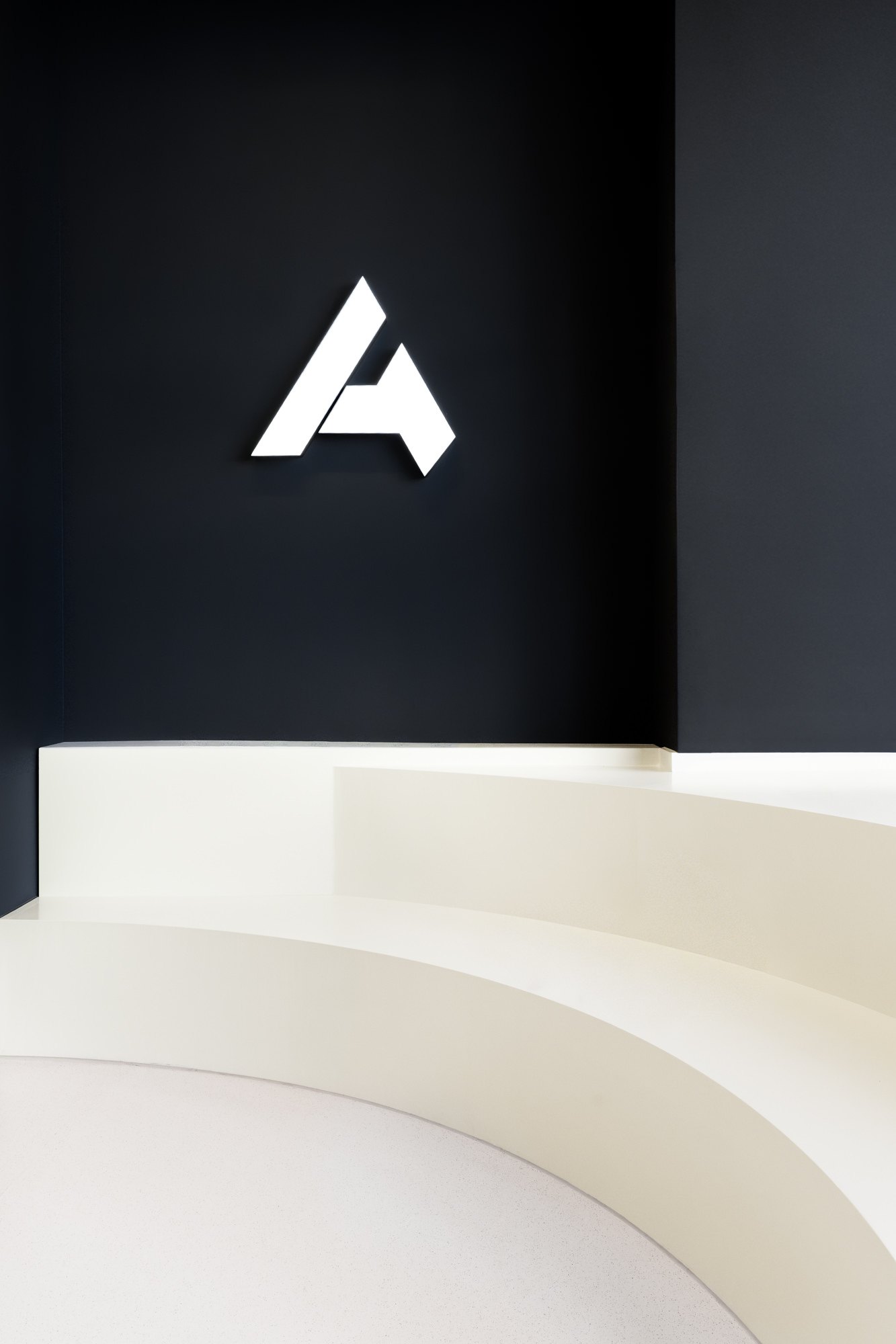 Beleuchtetes ATHLETICA Logo an einer dunkelblauen Wand über dem Empfangstresen