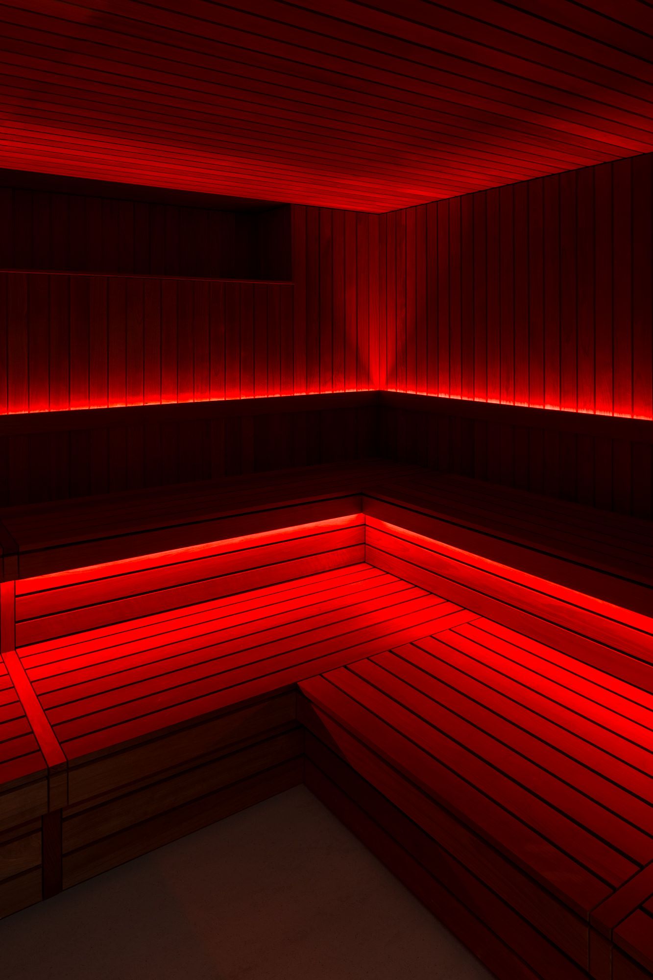 Sauna im ATHLETICA Bootcamp & Recovery, rotes Licht auf Holzbänken